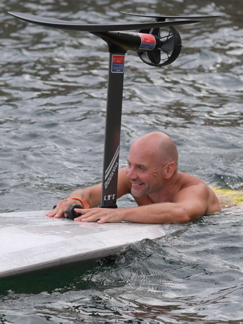 Male Escort Sascha sporty with an electric surfboard in the water